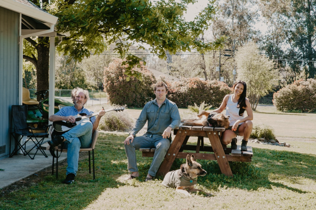 Bob playing guitar outdoors with Nick, Gladys and the dogs